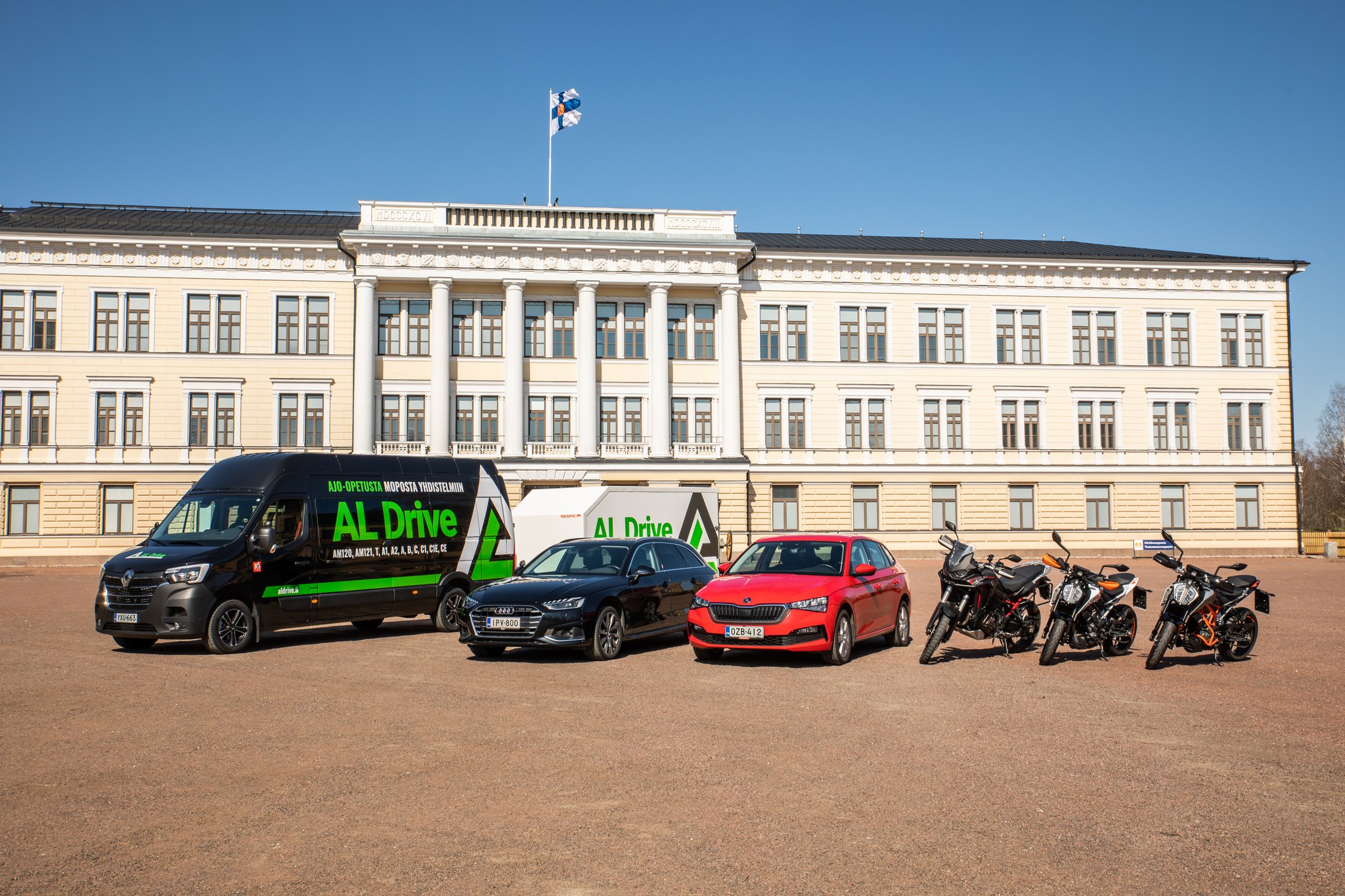 Lahikuva autokoulu AL Driven ajo-opetusauton takaa missa nakyy rekisterikilpi, yrityksen logo ja ajo-opetuksesta kertova valkoinen kolmio.